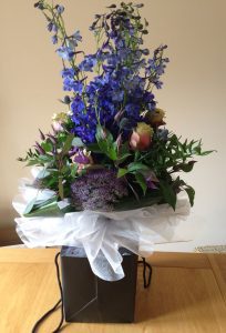 Boxed bouquet of blue delphiniums, clematis and roses