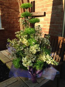 Boxed bouquet of green carnations and wax flower.